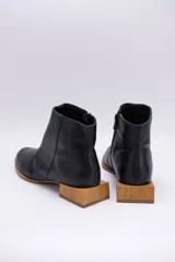 Botín de cuero dorado con punta fina y taco bajo cuadrado de madera.