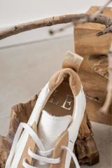 Championes de cuero con diseño de paneles en color blanco y tostado. Presentan suela de plataforma, cordones planos al tono y detalle de tirador en el talón.
