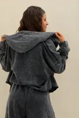 Campera crop estilo hoodie con capucha, cierre frontal completo y efecto acid wash en color negro, de mangas largas amplias y calce holgado.
