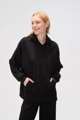 Canguro negro holgado con capucha y cordones ajustables, mangas largas y bolsillos laterales.