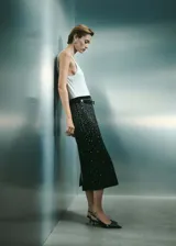 Falda midi de corte recto en color negro, confeccionada con detalle de strass brillante distribuido por toda la prenda. Presenta tiro medio y cintura con elástico para mayor comodidad.