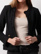 Chaqueta negra en tejido tweed de la marca Nanette. Tiene escote mao, abertura central y bolsillos delanteros. Los puños tienen apliques de botones perlados y la terminación es desflecada. Tiene forro interno.