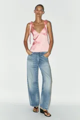 Top de satén rosado con escote en pico y tirantes finos que se atan con lazos.