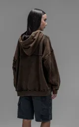 Hoodie de corte oversize y largo crop, confeccionado en algodón con efecto de desgaste y color óxido. Presenta costuras expuestas, detalles de roturas en los bordes y bolsillo frontal tipo canguro.