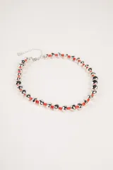 Collar corto compuesto por cuentas metálicas plateadas de forma irregular y pequeñas cuentas rojas intercaladas. Incluye cierre de mosquetón y cadena de extensión.