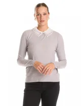 Buzo de punto fino color gris, con cuello camisero de gasa integrado decorado con apliques de perlas y brillos. Presenta mangas largas y puños acanalados.