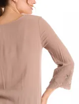Blusa de rayón color marrón con escote en V y mangas tres cuartos acampanadas. Presenta detalles de bordado suizo y calados florales en los puños y en el ruedo asimétrico con terminación festoneada.