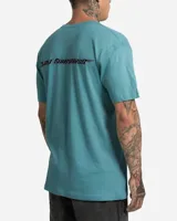 Remera de manga corta color verde agua, con cuello redondo y pequeño estampado gráfico circular en el pecho del lado izquierdo.