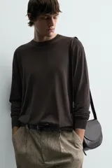 Jersey color crudo de tejido de punto, con cuello redondo y mangas largas. Corte amplio y terminaciones en rib.