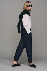 Pantalón chino de tiro bajo color marrón oscuro, con pernera recta y bajo con vuelta. Incluye un cinturón trenzado delgado de color marrón claro. Cuenta con bolsillos delanteros y cierre frontal con cremallera y botón.