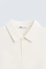 Polo de corte regular fit en tejido de piqué, color amarillo claro. Presenta cuello solapa, cierre frontal con botonadura y mangas cortas con acabados en rib.