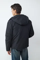 Campera acolchada negra con capucha integrada, cierre frontal de cremallera y bolsillos laterales con cierre.