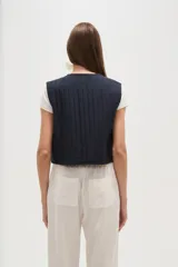 Chaleco sin mangas, color azul marino, con bordados florales en tono celeste claro. Presenta un escote en V y se cierra al frente con lazos ajustables.