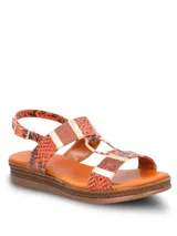 Sandalia Hush Puppies en colaboración con Massimo Cerutti, con plataforma baja y tiras con estampado de piel de serpiente en tonos naranja, combinadas con detalles metálicos, apliques con glitter y una argolla dorada central. Cuenta con tira ajustable con hebilla en el talón.
