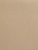 Cartera bandolera color beige de cuero sintético granulado, con correa de cadena plateada y cierre de solapa con placa metálica con logo grabado.