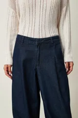 Pantalón tipo jean azul oscuro, de corte slouchy con pinzas en la cintura, bolsillos laterales y puños fruncidos con elástico en los tobillos.