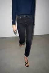 Jeans mom fit de tiro alto color negro con efecto lavado, diseño de cinco bolsillos y corte tobillero.