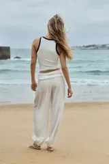 Pantalón blanco de corte globo con cintura ancha fruncida y bajos elásticos. El tejido presenta una textura arrugada.