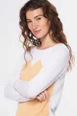 Buzo de tejido de punto con diseño bicolor, combinando blanco en la parte superior y mangas con un tono celeste grisáceo en el cuerpo, presentando un patrón geométrico en la unión de los colores. Posee cuello redondo y mangas largas.