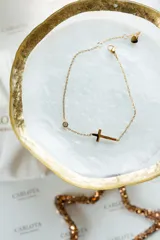 Tobillera dorada con cadena fina, dije de cruz horizontal y dije de circonita redonda.