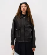 Campera de estilo urbano con corte oversized, confeccionada en poliuretano con base de poliéster. Presenta cuello clásico, cierre frontal con botones a presión, mangas largas y dos bolsillos frontales con tapa. El bajo cuenta con elástico para un mejor ajuste.