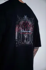 Remera oversize de algodón elastizado en color negro, con diseño gráfico estampado en la espalda que representa un arco gótico con detalles en rojo y texto.