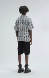 Camisa de manga corta, tejida de punto abierto (símil crochet), color blanco y negro con estampado paisley. Tiene cuello tipo solapa y calce oversize.