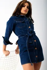 Vestido corto de denim azul con cierre frontal de botones metálicos, bolsillos con solapa en el pecho y cinturón ajustable del mismo material.