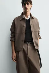 Sobrecamisa negra de corte boxy fit en tejido compacto, con cuello solapa, manga larga con puño abotonado, bolsillos frontales aplicados y cierre frontal de botonadura.