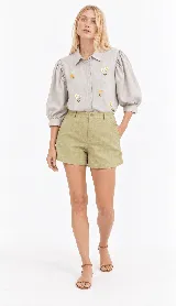 Camisa clásica de lino natural color blanco, con mangas abullonadas tres cuartos y delicados bordados artesanales de flores en el frente.