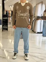 Sweater marrón de tejido de punto acanalado, con cuello polo en color marfil y cierre frontal en V. Presenta inscripciones y logotipos bordados en el pecho, incluyendo la palabra "Concept" en tipografía cursiva y "ALL GOOD FEELS" en la parte inferior.