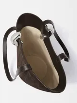 Bolso de mano tipo cubo asimétrico, confeccionado en ante con textura de relieve de cocodrilo. Presenta asas superiores, cierre con anilla metálica plateada y logo de la marca en la parte frontal.