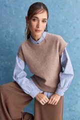 Chaleco tejido de punto color tostado, con escote redondo, hombros caídos y terminaciones acanaladas en cuello, sisas y ruedo.