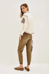 Pantalón tipo babucha de gabardina elastizada, color negro, con cintura elástica ajustable mediante cordón, puños en los tobillos, bolsillos diagonales frontales y bolsillos traseros con solapa y botón.