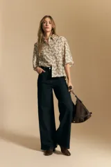 Camisa de manga corta con cuello camisero, confeccionada en tela estampada con diseño paisley en tonos negro, beige y azul.