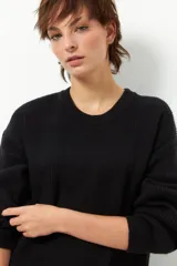 Sweater color borgoña de manga larga, tejido tramado y cuello redondo con puños elastizados.