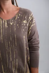 Sweater de viscosa color visón con escote en V y mangas largas. Presenta un estampado de rayas verticales y salpicaduras en color dorado.