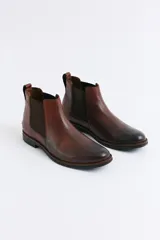 Bota tipo Chelsea de cuero negro con paneles elásticos laterales, suela de goma con detalle de vira en contraste y tirador trasero.