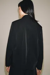 Blazer cruzado Zara de color negro, con cuello de solapa, manga larga y bolsillos laterales ocultos en la costura. Cuenta con cierre frontal de botones.
