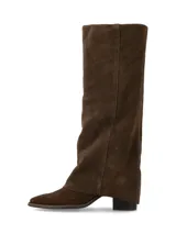 Bota de caña alta confeccionada en cuero gamuza color chocolate, con diseño de polaina incorporada y taco bajo.