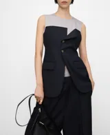 Top combinado de efecto doble prenda con base gris de rayas y capa superpuesta azul marino tipo chaleco sastrero, con cuello redondo, manga sisa, botones frontales y bolsillos con solapa.