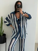 Conjunto de dos piezas tejido a crochet con diseño de rayas verticales en azul y blanco. Incluye una camisa de manga corta con cierre frontal de botones y un pantalón de corte recto y tiro alto con cintura elástica.