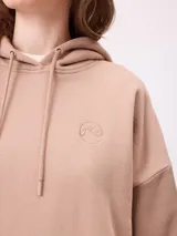 Canguro negro de corte holgado con capucha y cordones ajustables. Presenta un bolsillo frontal tipo canguro y un pequeño logo bordado en el pecho.