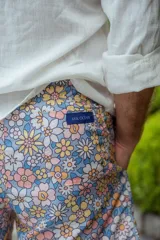 Short de baño con estampado de flores en tonos pastel sobre fondo celeste.