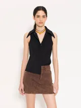 Camisa sin mangas confeccionada en tela de punto lisa, color negro, de corte regular. Lleva cartera con broches JCH y pinzas que entallan la prenda.