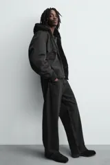 Cazadora bomber reversible de corte relajado confeccionada en tejido técnico. Presenta capucha con interior de pelo sintético, cierre frontal con cremallera de doble dirección, bolsillos laterales y puños y bajo con acabado en rib elástico.