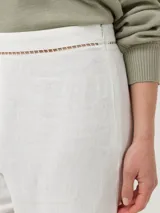 Pantalón de lino orgánico y viscosa, de color blanco y corte recto con tiro alto. Presenta detalles de calados sutiles en la cintura y en los dobladillos.