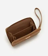 Billetera pequeña de poliuretano texturizado color tostado, con cierre perimetral de cremallera, correa de mano extraíble y detalle metálico decorativo en el frente.