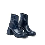 Botas cortas negras de cuero vacuno con textura tipo cocodrilo. Taco de madera forrado en cuero de 8cm, entre suela de goma de 2cm forrada en cuero, inclinación de horma de 6cm y caña de 15cm. Cierre YKK del lado interno y horma de punta cuadrada.