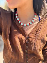 Collar corto con cuentas de cerámica rojas y celestes en forma de estrella. Se cierra con cadena y ganchito para regular el largo.